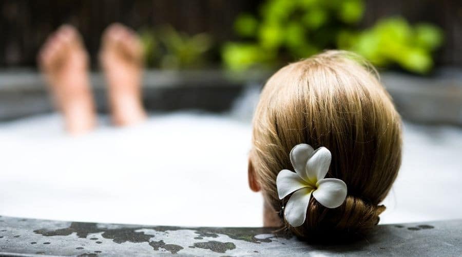 A person in a hot tub with bubbles and greenery, showcasing a relaxing spa environment. Scott Plumbing supports wellness.