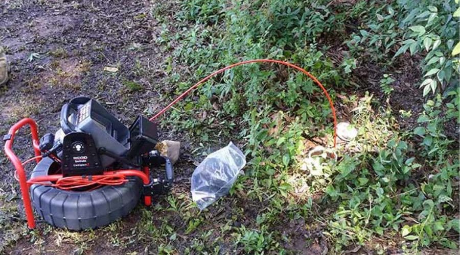 Outdoor plumbing equipment with a red hose and tire support, used for maintenance; showcasing Scott Plumbing services.