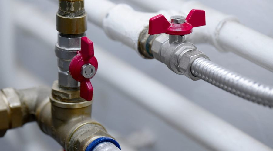 Close-up of plumbing with brass pipes and red valve handles, showcasing Scott Plumbing maintenance solutions.