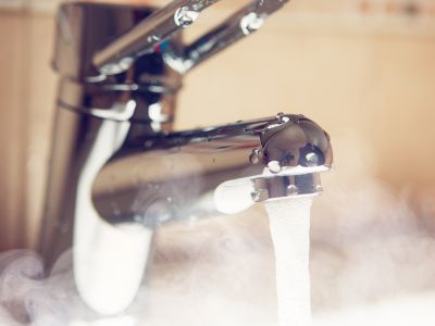 Faucet with steaming hot water flowing, illustrating the benefits of tankless water heaters for endless hot water supply and energy efficiency.