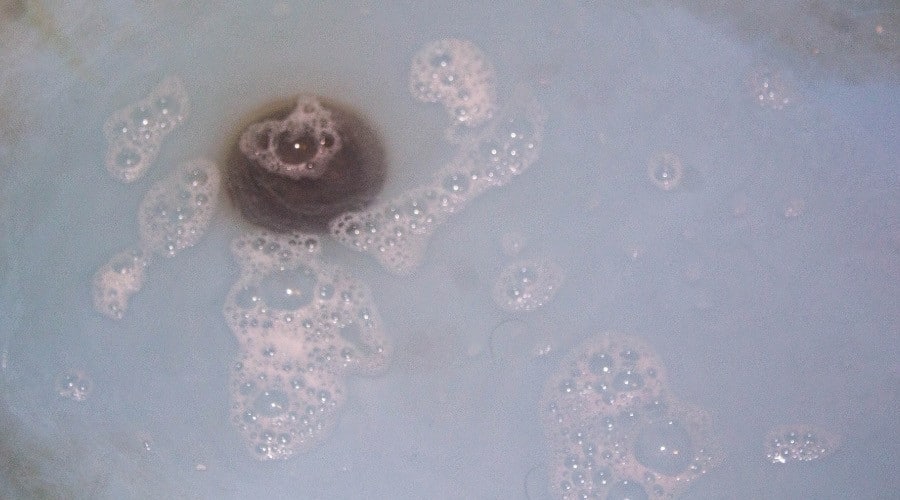 Bubbling water in a sink with a visible drain, illustrating potential signs of a sewer line clog as discussed in plumbing maintenance and drain cleaning guidance.